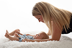 Mutter schaut liegendes Baby an und lächelt